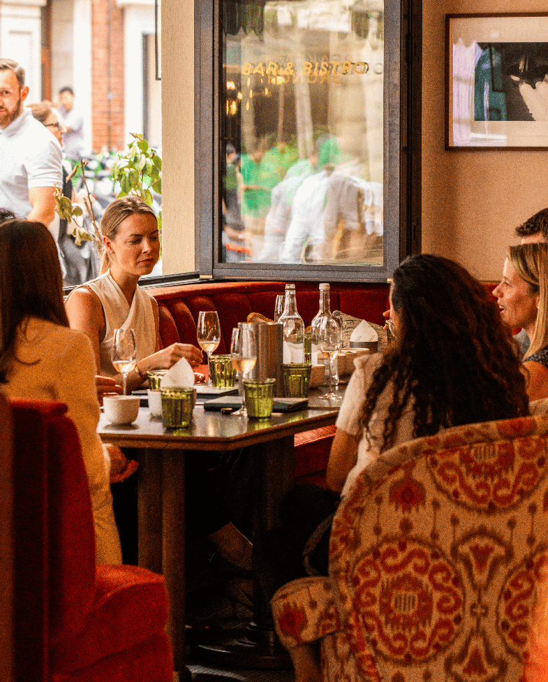 Group dining and drinks round a table at Nessa Soho
