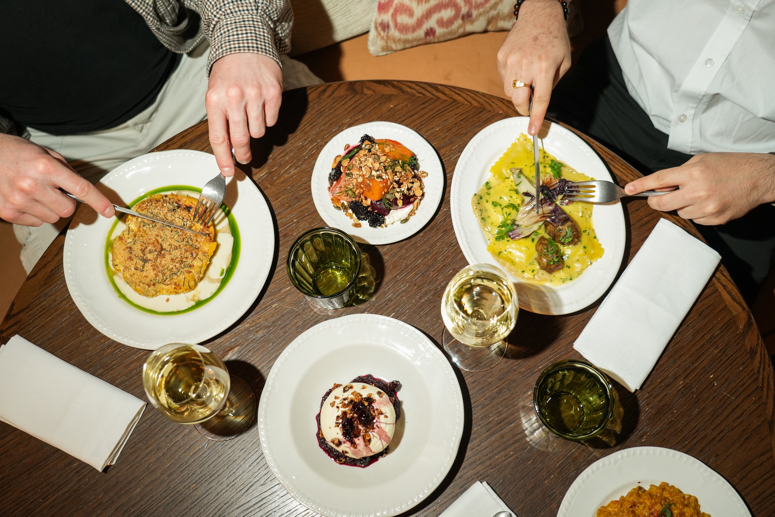 Overhead view of two people dining on colorful modern British dishes with white wine at Nessa restaurant in Soho