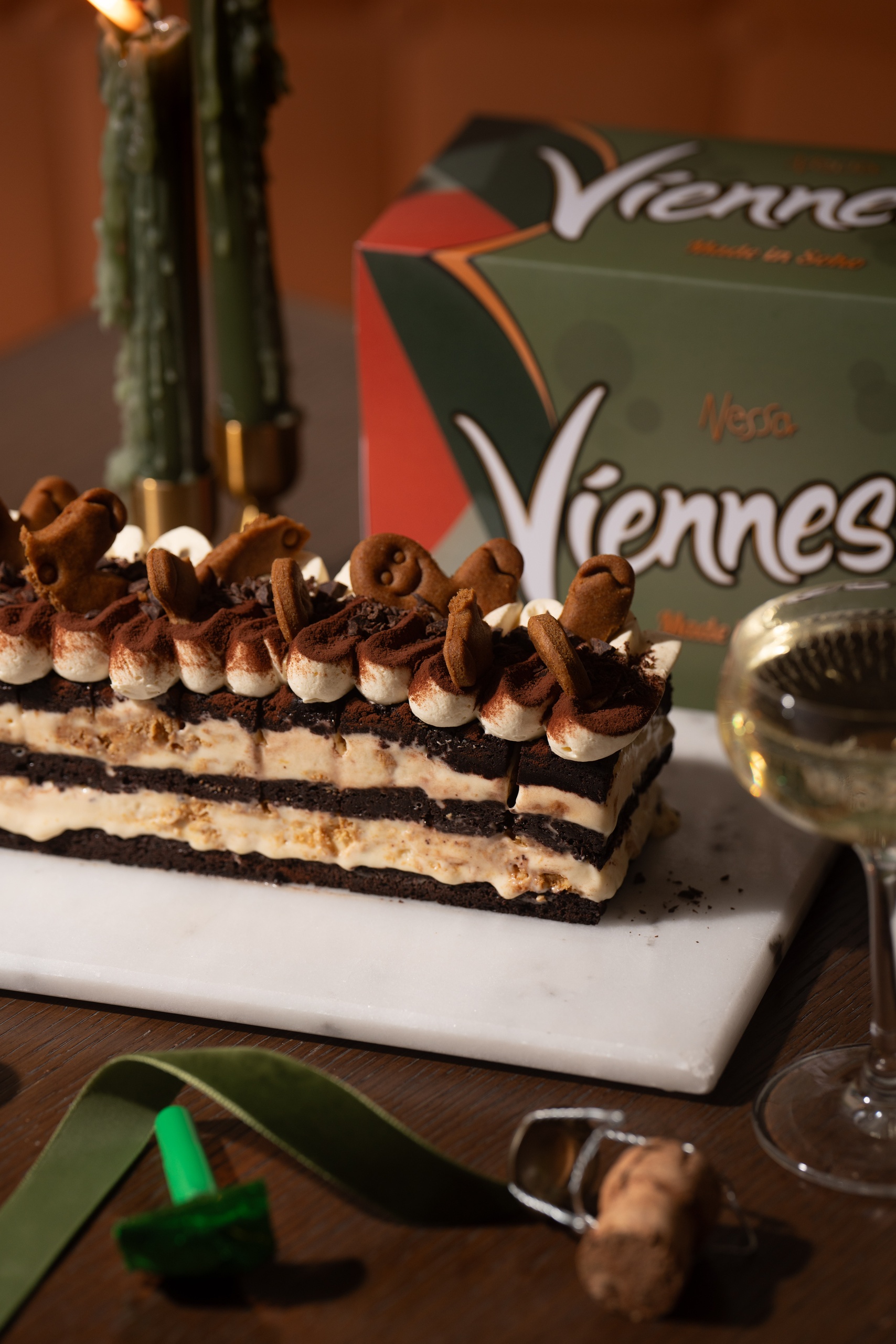 Layered chocolate and vanilla ice cream cake topped with whipped cream and gingerbread cookies, next to a Viennessa box